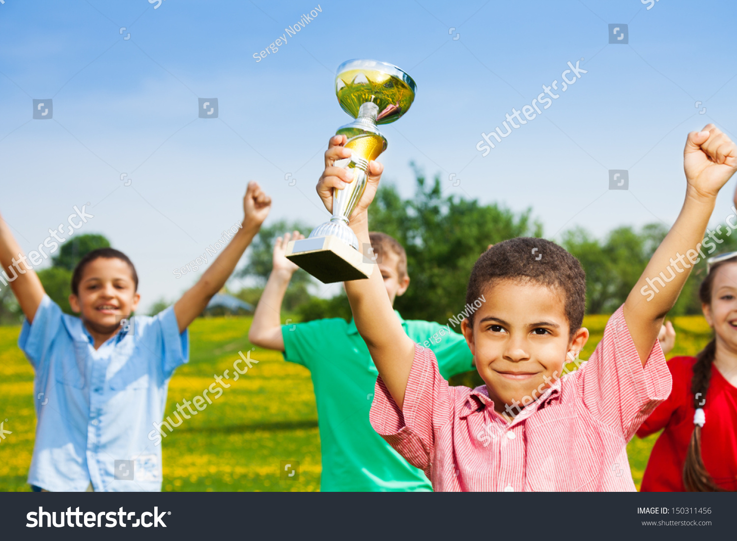 close shoot of black happy smiling little boy holding prize cup