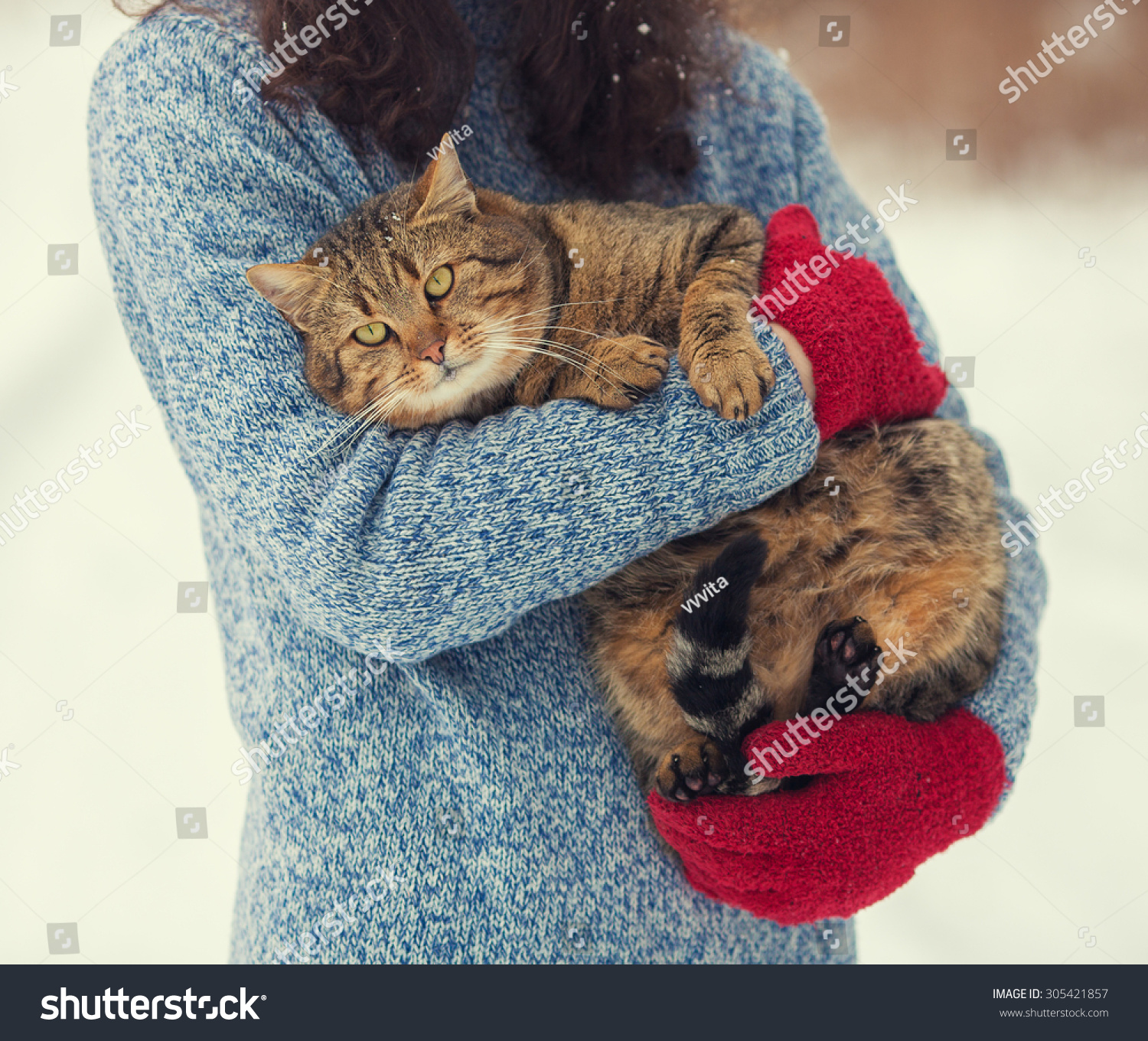 年轻女子抱着一只猫在冬天在户外