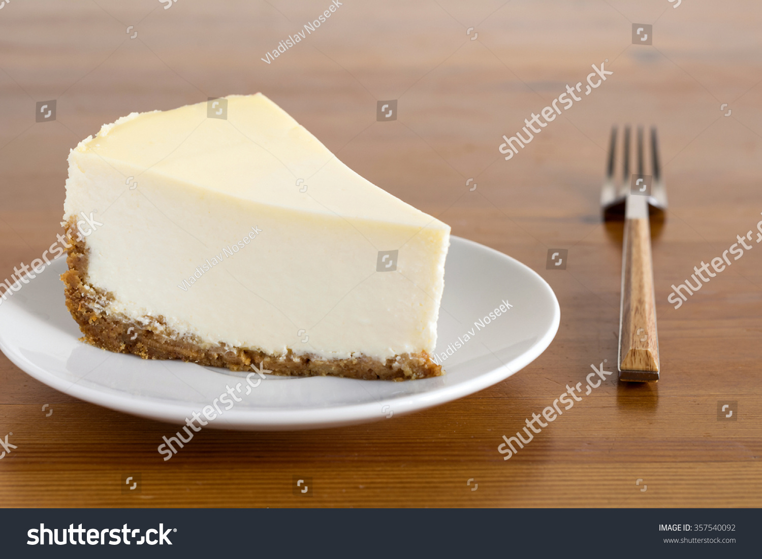 slice of plain new york cheesecake on white plate on wooden back